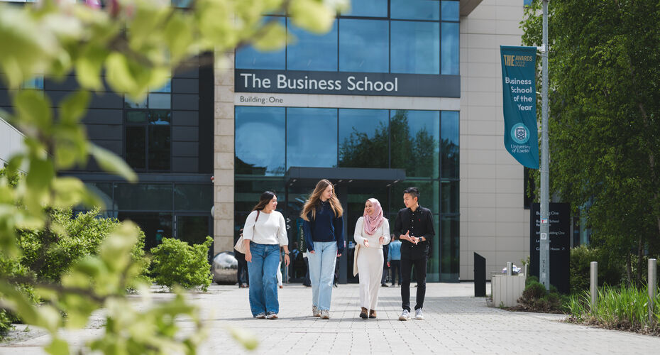 A group of students walking in front of the university of exeter business school building.