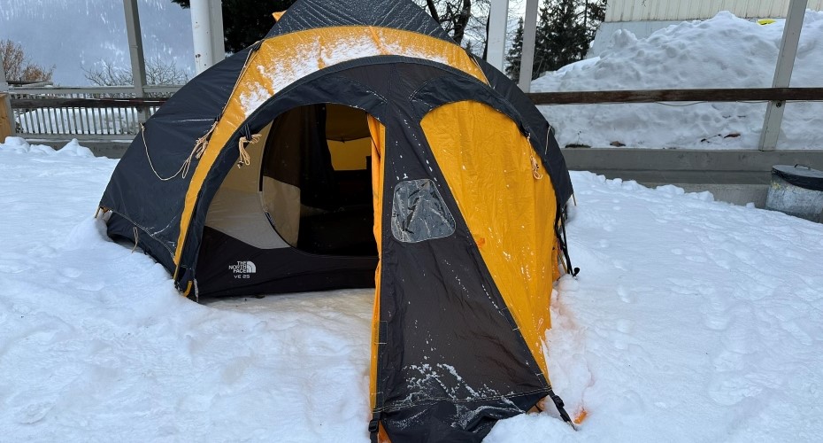 Snow-covered ground with black and yellow tent.