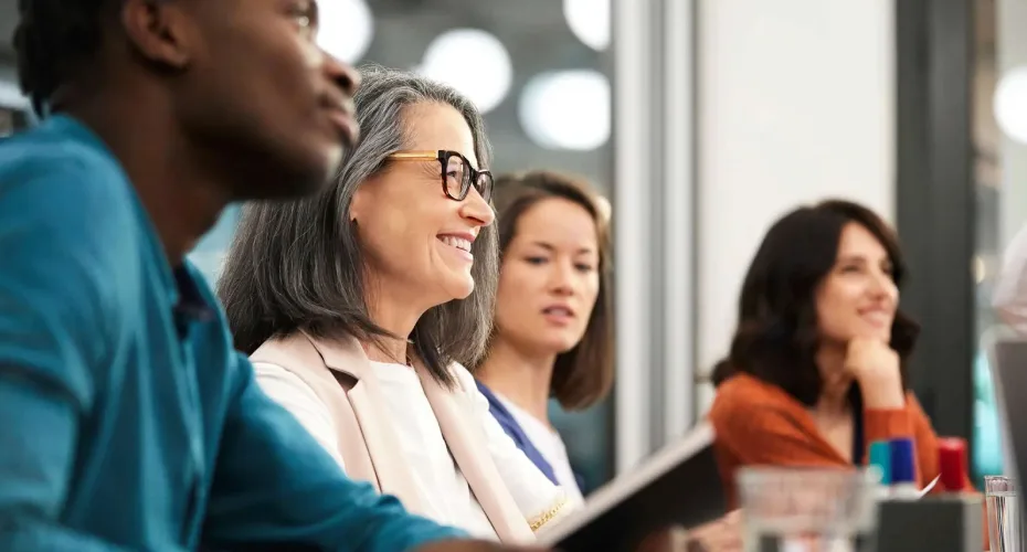 A diverse group of individuals engaged in a meeting, seated around a conference table.