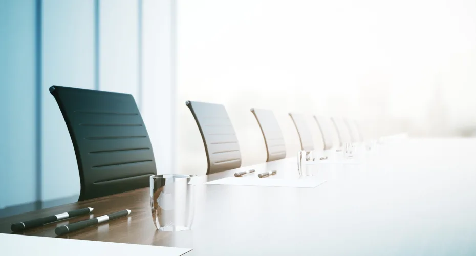 Conference table with chairs and a glass of water.