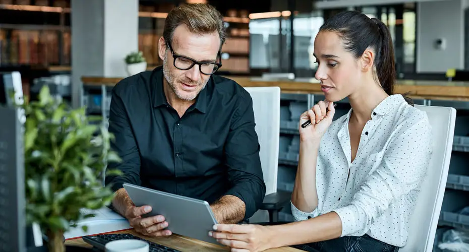 An employer and an apprentice looking at a laptop