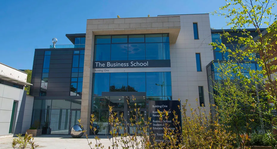 Front view of the Business School at the University of Exeter, showcasing its modern architecture and surrounding landscape.