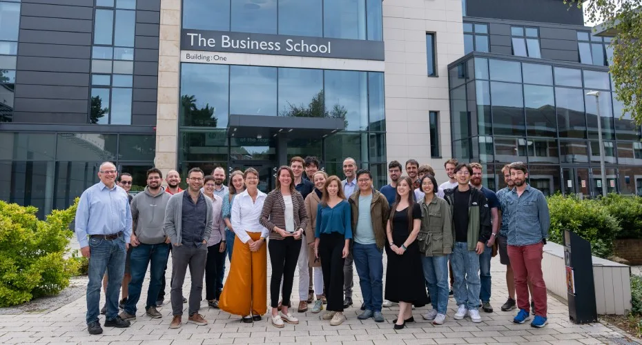 Exeter prize entries standing outside building one at the university of exeter business school.