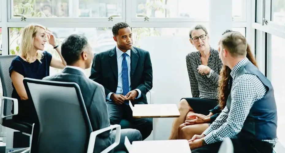 A diverse group of professionals engaged in a meeting, discussing business matters around a conference table.
