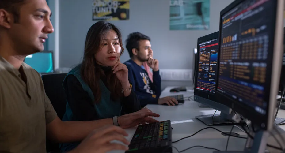 Business Analytics students looking at a data dashboard on a computer.