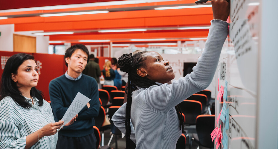 A group of mba students in an office, participating in workshops with visiting speaker john amaechi obe.