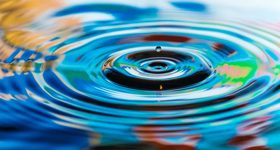 A close-up of a water droplet reflecting a vibrant, colorful background.