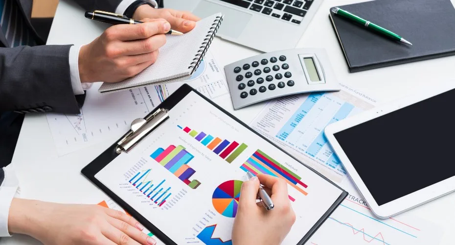 Business professionals collaborating on a laptop and tablet in a modern office setting.