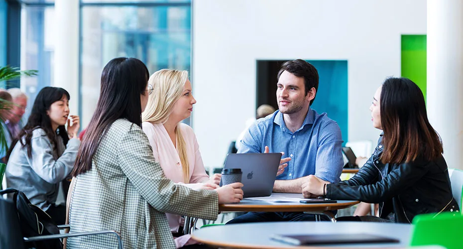 University staff members engaged in discussion around a table in a meeting room.